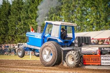 Aarhus, Danimarka. 16 Ağustos 2025 Güçlü makinelerin neşeli festival kalabalığından önce ağır topları çamura sürüklediği bir yarışma..