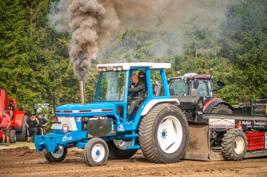 Aarhus, Danimarka. 16 Ağustos 2025 Güçlü makinelerin neşeli festival kalabalığından önce ağır topları çamura sürüklediği bir yarışma..