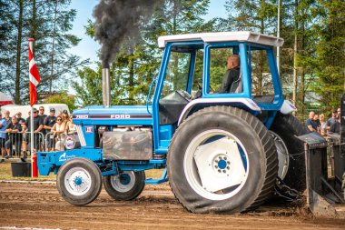 Aarhus, Danimarka. 16 Ağustos 2025 Güçlü makinelerin neşeli festival kalabalığından önce ağır topları çamura sürüklediği bir yarışma..