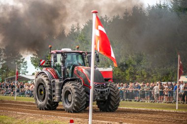Aarhus, Danimarka. 16 Ağustos 2025 Güçlü makinelerin neşeli festival kalabalığından önce ağır topları çamura sürüklediği bir yarışma..