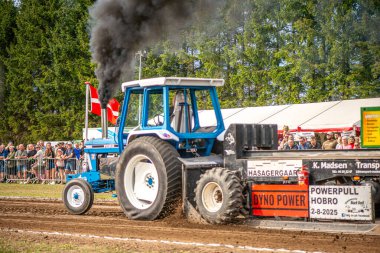 Aarhus, Danimarka. 16 Ağustos 2025 Güçlü makinelerin neşeli festival kalabalığından önce ağır topları çamura sürüklediği bir yarışma..