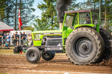 Aarhus, Danimarka. 16 Ağustos 2025 Güçlü makinelerin neşeli festival kalabalığından önce ağır topları çamura sürüklediği bir yarışma..