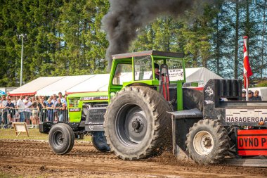 Aarhus, Danimarka. 16 Ağustos 2025 Güçlü makinelerin neşeli festival kalabalığından önce ağır topları çamura sürüklediği bir yarışma..