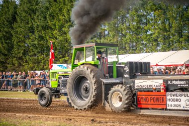 Aarhus, Danimarka. 16 Ağustos 2025 Güçlü makinelerin neşeli festival kalabalığından önce ağır topları çamura sürüklediği bir yarışma..