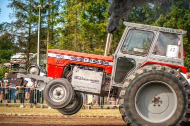 Aarhus, Danimarka. 16 Ağustos 2025 Güçlü makinelerin neşeli festival kalabalığından önce ağır topları çamura sürüklediği bir yarışma..
