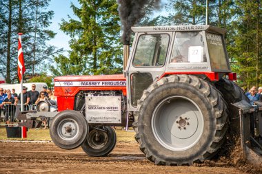 Aarhus, Danimarka. 16 Ağustos 2025 Güçlü makinelerin neşeli festival kalabalığından önce ağır topları çamura sürüklediği bir yarışma..