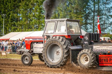 Aarhus, Danimarka. 16 Ağustos 2025 Güçlü makinelerin neşeli festival kalabalığından önce ağır topları çamura sürüklediği bir yarışma..