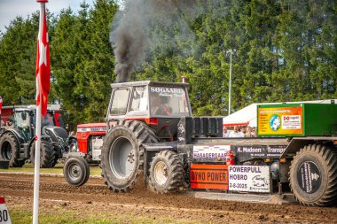 Aarhus, Danimarka. 16 Ağustos 2025 Güçlü makinelerin neşeli festival kalabalığından önce ağır topları çamura sürüklediği bir yarışma..