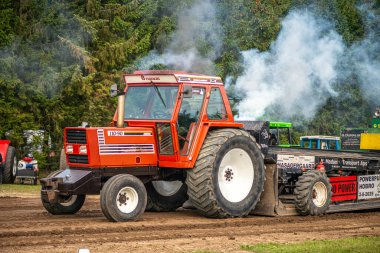 Aarhus, Danimarka. 16 Ağustos 2025 Güçlü makinelerin neşeli festival kalabalığından önce ağır topları çamura sürüklediği bir yarışma..