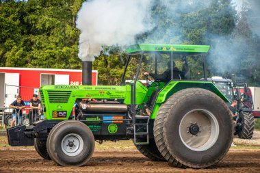 Aarhus, Danimarka. 16 Ağustos 2025 Güçlü makinelerin neşeli festival kalabalığından önce ağır topları çamura sürüklediği bir yarışma..