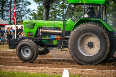 Aarhus, Danimarka. 16 Ağustos 2025 Güçlü makinelerin neşeli festival kalabalığından önce ağır topları çamura sürüklediği bir yarışma..