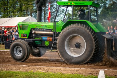 Aarhus, Danimarka. 16 Ağustos 2025 Güçlü makinelerin neşeli festival kalabalığından önce ağır topları çamura sürüklediği bir yarışma..