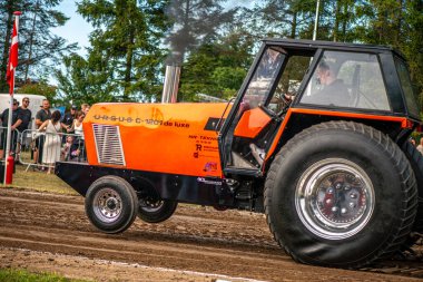 Aarhus, Danimarka. 16 Ağustos 2025 Güçlü makinelerin neşeli festival kalabalığından önce ağır topları çamura sürüklediği bir yarışma..
