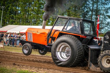 Aarhus, Danimarka. 16 Ağustos 2025 Güçlü makinelerin neşeli festival kalabalığından önce ağır topları çamura sürüklediği bir yarışma..