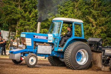 Aarhus, Danimarka. 16 Ağustos 2025 Güçlü makinelerin neşeli festival kalabalığından önce ağır topları çamura sürüklediği bir yarışma..