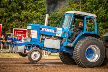 Aarhus, Danimarka. 16 Ağustos 2025 Güçlü makinelerin neşeli festival kalabalığından önce ağır topları çamura sürüklediği bir yarışma..