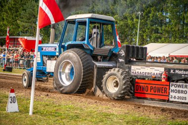 Aarhus, Danimarka. 16 Ağustos 2025 Güçlü makinelerin neşeli festival kalabalığından önce ağır topları çamura sürüklediği bir yarışma..
