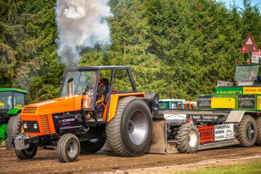 Aarhus, Danimarka. 16 Ağustos 2025 Güçlü makinelerin neşeli festival kalabalığından önce ağır topları çamura sürüklediği bir yarışma..