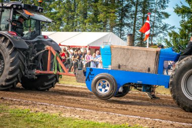 Aarhus, Danimarka. 16 Ağustos 2025 Güçlü makinelerin neşeli festival kalabalığından önce ağır topları çamura sürüklediği bir yarışma..