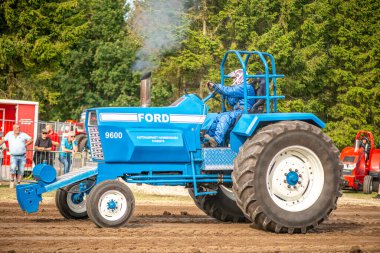 Aarhus, Danimarka. 16 Ağustos 2025 Güçlü makinelerin neşeli festival kalabalığından önce ağır topları çamura sürüklediği bir yarışma..