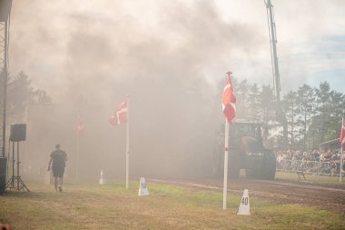 Aarhus, Danimarka. 16 Ağustos 2025 Güçlü makinelerin neşeli festival kalabalığından önce ağır topları çamura sürüklediği bir yarışma..