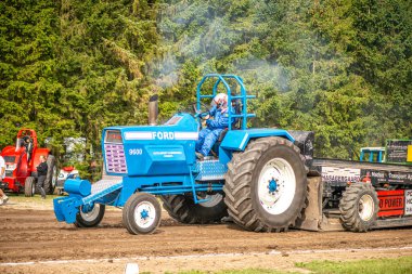 Aarhus, Danimarka. 16 Ağustos 2025 Güçlü makinelerin neşeli festival kalabalığından önce ağır topları çamura sürüklediği bir yarışma..