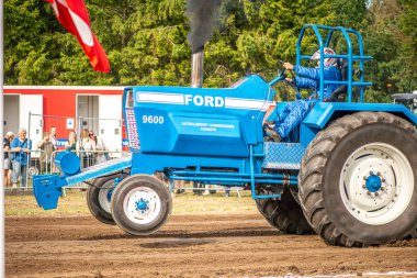 Aarhus, Danimarka. 16 Ağustos 2025 Güçlü makinelerin neşeli festival kalabalığından önce ağır topları çamura sürüklediği bir yarışma..