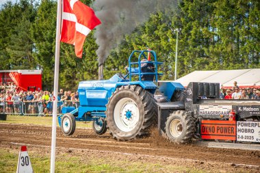 Aarhus, Danimarka. 16 Ağustos 2025 Güçlü makinelerin neşeli festival kalabalığından önce ağır topları çamura sürüklediği bir yarışma..