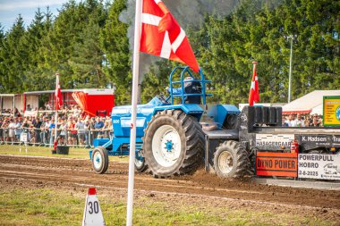 Aarhus, Danimarka. 16 Ağustos 2025 Güçlü makinelerin neşeli festival kalabalığından önce ağır topları çamura sürüklediği bir yarışma..