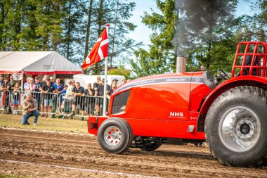 Aarhus, Danimarka. 16 Ağustos 2025 Güçlü makinelerin neşeli festival kalabalığından önce ağır topları çamura sürüklediği bir yarışma..
