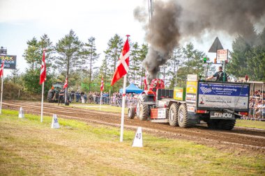 Aarhus, Danimarka. 16 Ağustos 2025 Güçlü makinelerin neşeli festival kalabalığından önce ağır topları çamura sürüklediği bir yarışma..
