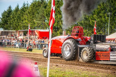Aarhus, Danimarka. 16 Ağustos 2025 Güçlü makinelerin neşeli festival kalabalığından önce ağır topları çamura sürüklediği bir yarışma..