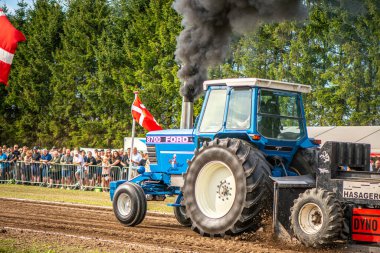 Aarhus, Danimarka. 16 Ağustos 2025 Güçlü makinelerin neşeli festival kalabalığından önce ağır topları çamura sürüklediği bir yarışma..
