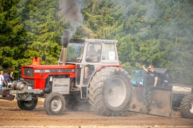Aarhus, Danimarka. 16 Ağustos 2025 Güçlü makinelerin neşeli festival kalabalığından önce ağır topları çamura sürüklediği bir yarışma..