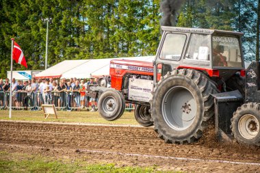Aarhus, Danimarka. 16 Ağustos 2025 Güçlü makinelerin neşeli festival kalabalığından önce ağır topları çamura sürüklediği bir yarışma..