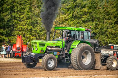Aarhus, Danimarka. 16 Ağustos 2025 Güçlü makinelerin neşeli festival kalabalığından önce ağır topları çamura sürüklediği bir yarışma..