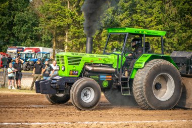 Aarhus, Danimarka. 16 Ağustos 2025 Güçlü makinelerin neşeli festival kalabalığından önce ağır topları çamura sürüklediği bir yarışma..