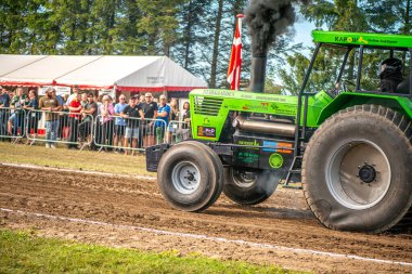 Aarhus, Danimarka. 16 Ağustos 2025 Güçlü makinelerin neşeli festival kalabalığından önce ağır topları çamura sürüklediği bir yarışma..