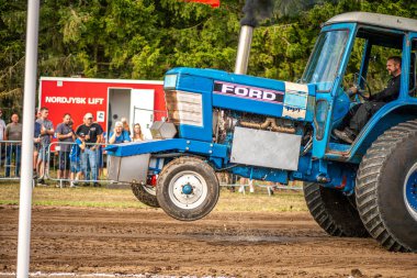 Aarhus, Danimarka. 16 Ağustos 2025 Güçlü makinelerin neşeli festival kalabalığından önce ağır topları çamura sürüklediği bir yarışma..