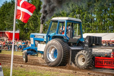 Aarhus, Danimarka. 16 Ağustos 2025 Güçlü makinelerin neşeli festival kalabalığından önce ağır topları çamura sürüklediği bir yarışma..