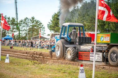 Aarhus, Danimarka. 16 Ağustos 2025 Güçlü makinelerin neşeli festival kalabalığından önce ağır topları çamura sürüklediği bir yarışma..