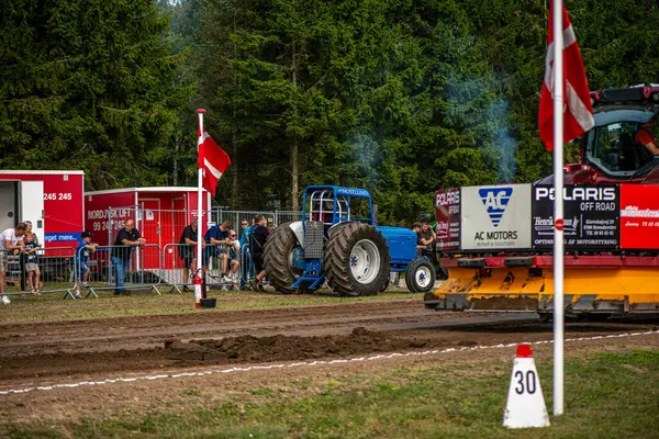 Aarhus, Danimarka. 16 Ağustos 2025 Güçlü makinelerin neşeli festival kalabalığından önce ağır topları çamura sürüklediği bir yarışma..
