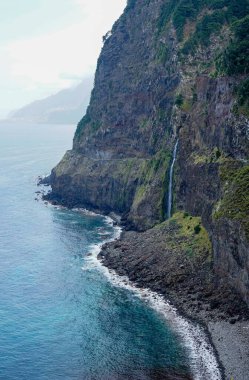 Bir dağ yamacından çarpıcı bir okyanus manzarası kayalık kıyılara çarpan dalgaları ortaya çıkarır. Canlı mavi sular ve bereketli yeşillik huzur ve hayranlık uyandıran büyüleyici bir manzara yaratır..