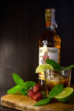 Masada bir bardak viski, buz ve limon var.