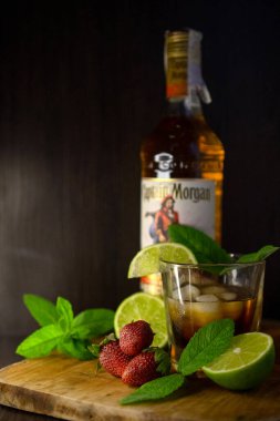 Bir bardak soğuk rom, naneli, buzlu ve limonlu eski masada bir bardak viskiyle.