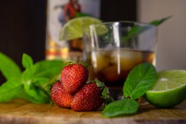 Masanın üzerinde nane yaprakları olan bir bardak kırmızı şarap.