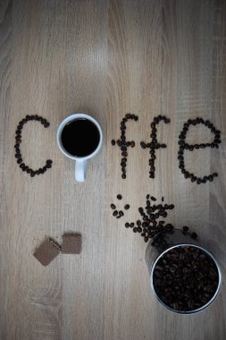 Kahve fincanı ve kahve çekirdekleri ahşap masada.