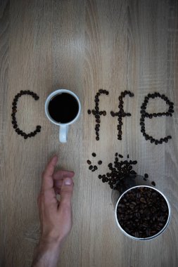 Kahve çekirdekli bir fincan kahve ve ahşap bir masada harfler..