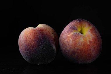 İki olgun şeftali, siyah arka planda izole edilmiş.