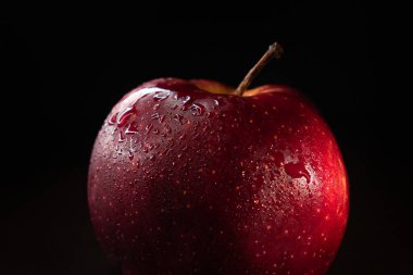 Siyah zemin üzerinde su damlaları olan kırmızı elma